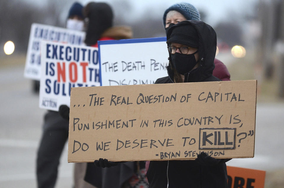 Christina Bollo of Urbana, Illinois, holds a sign as she protests the execution of Corey Johnson, near the Federal Correctional Complex, Thursday, Jan. 14, 2021, in Terre Haute, Ind. (Joseph C. Garza/The Tribune-Star via AP)