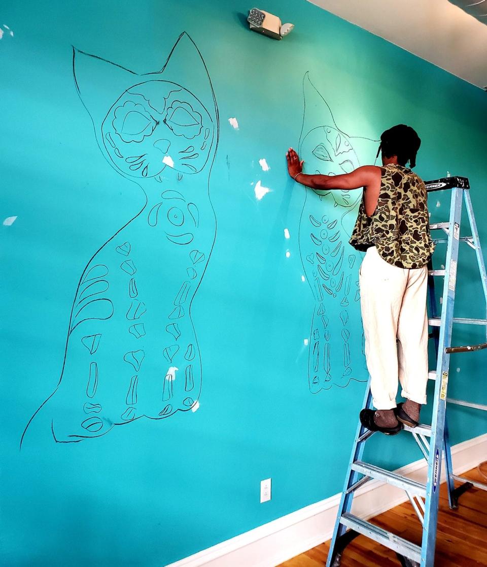 Artist Jaylon "Huey" Bost paints a mural on the wall inside Loco Kitty in Old Towne Petersburg.