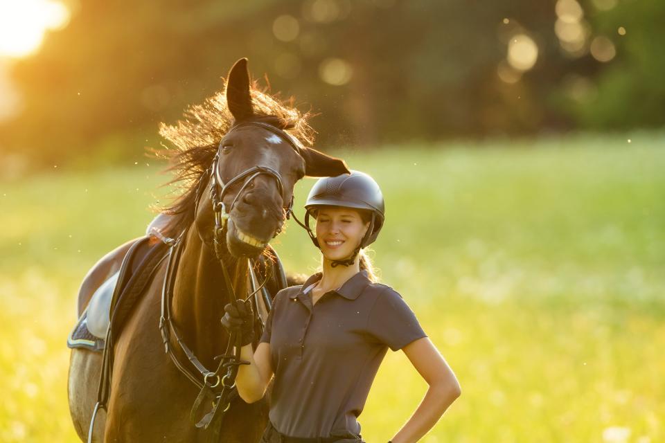 A woman stands with her horse, who appears to be laughing at her joke.