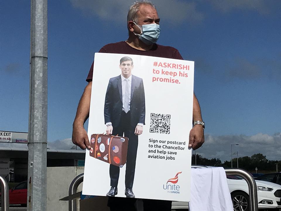 An aviation worker holds a banner challenging Chancellor Rishi Sunak to intervene to protect jobs (Rebecca Black/PA)