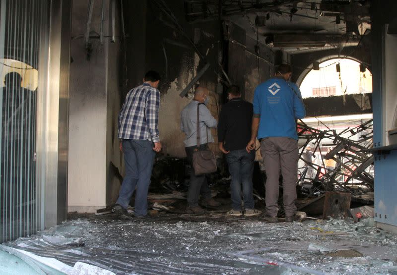 People inspect a bank after it was set ablaze during unrest overnight in Tripoli
