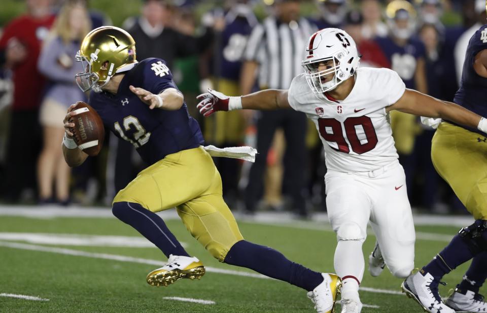 Notre Dame quarterback Ian Book scrambles away from Stanford linebacker Gabe Reid (90) during the first half of an NCAA college football game against Stanford, Saturday, Sept. 29, 2018, in South Bend, Ind. (AP Photo/Carlos Osorio)