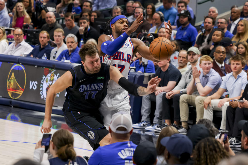 Dallas Mavericks guard Luka Doncic (77) and Philadelphia 76ers guard Buddy Hield (17) attempt to grab a loose ball while running out of bounds during the first half of an NBA basketball game, Sunday, March 3, 2024, in Dallas. (AP Photo/Gareth Patterson)