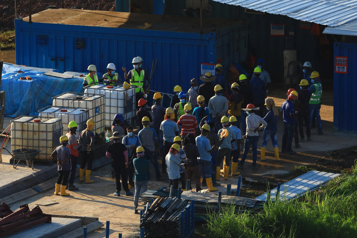 SINGAPORE - JUNE 09:  Workers wearing protective mask assemble for a briefing at a construction site of a quick-build dormitory on June 9, 2020 in Singapore. The government announced that it will build up to eight quick-build dormitories to house migrant workers who have been cleared of COVID-19. The temporary structures which can last about two to three years can house about 25,000 people. To date, Singapore has reported a total of 38,296 of COVID-19 infections, with the vast majority linked to crowded migrant workers living in dormitories.  (Photo by Suhaimi Abdullah/Getty Images)