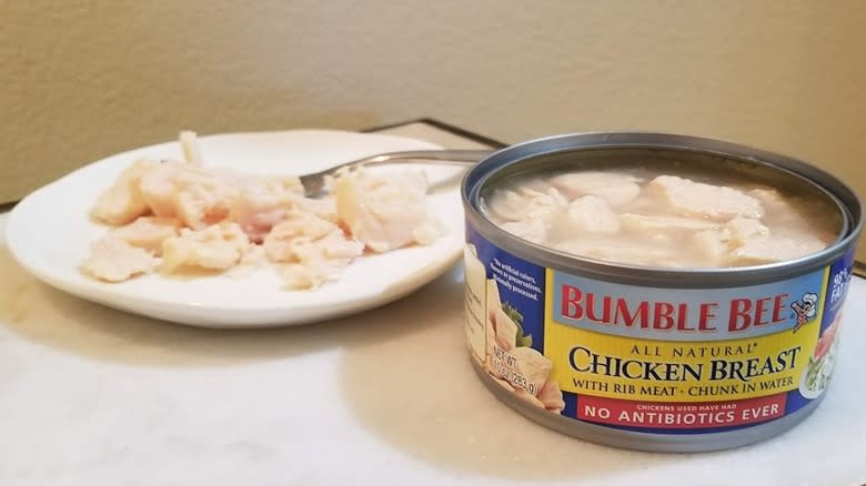 An open can of Bumble Bee canned chicken next to a plate with canned chicken