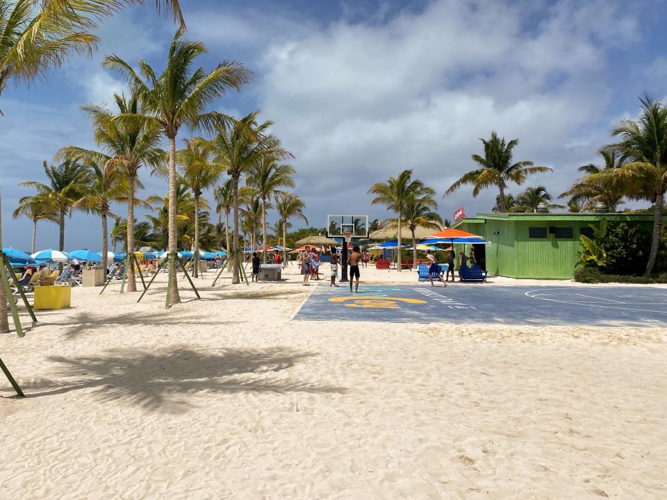 A basketball court at the beach in CocoCay with palm trees all around on a cloudy day