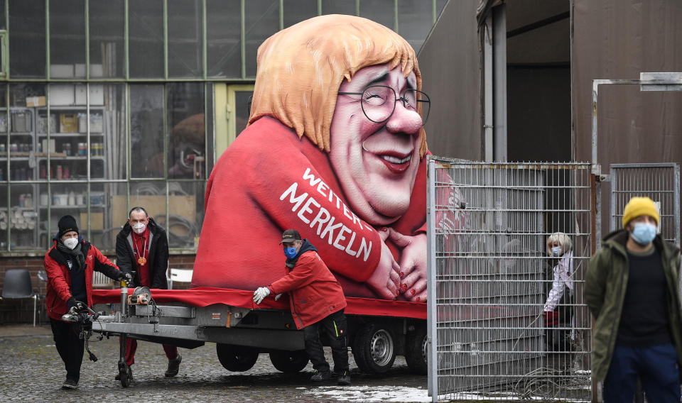 A political carnival float depicting German chancellor Angela Merkel and her possible successor Governor Armin Laschet is rolled out to be shown in the streets of Duesseldorf, Germany, Monday, Feb. 15, 2021. Because of the coronavirus pandemic the traditional; carnival parades are canceled but eight floats are pulled through the empty streets in Duesseldorf, where normally hundreds of thousands of people would celebrate the street carnival. (AP Photo/Martin Meissner)