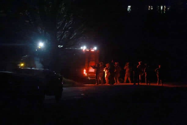 Law Enforcement officials gather near a home as they prepare to search it for the suspect in connection with two mass shootings on 26 October 2023 (Getty Images)