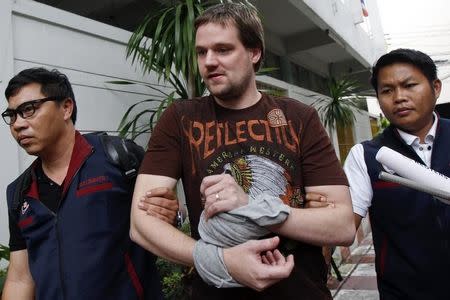 Hans Fredrik Lennart Neij (C), a co-founder of the Swedish file-sharing website, The Pirate Bay, is escorted by Thai police officers as he arrives at the Immigration Detention Center in Bangkok November 5, 2014. REUTERS/Chaiwat Subprasom