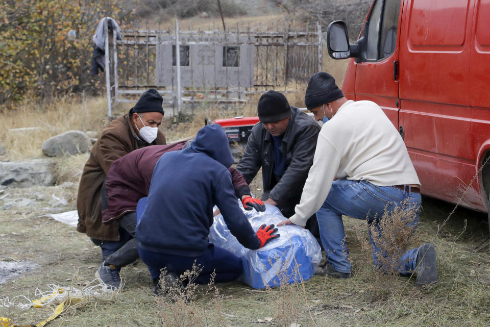 Ethnic Armenians prepare a coffin with the body of their relative Sergei Gabrilyan, moved from a grave, to repatriate his remains to Armenia, in Kalbajar in separatist region of Nagorno-Karabakh, Monday, Nov. 16, 2020. It is unclear when any civilians might try to settle in Karvachar, which will now be known by its Azeri name Kalbajar, or elsewhere. Armenians who are going to leave separatist region of Nagorno-Karabakh dig up the remains of their ancestors to bring them from the territory, which is to be handed over to Azerbaijanis. (AP Photo/Sergei Grits)