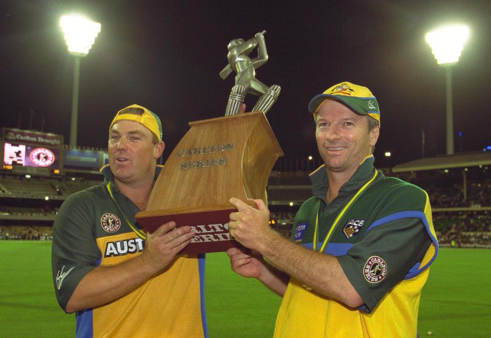 Shane Warne and Steve Waugh celebrate and lift the trophy.