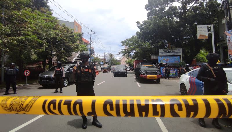 Armed police officers stand guard along a closed road following an explosion outside a Catholic church in Makassar, Indonesia