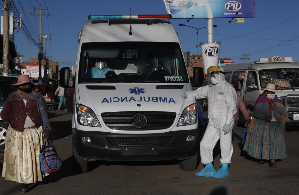 A healthcare worker in full protective gear stands next to an ambulance waiting to drop off a COVID-19 patient at the Del Norte Hospital, in El Alto, Bolivia, Wednesday, July 8, 2020. According to doctors at the facility, the hospital is at full capacity, including its ICU unit. (AP Photo/Juan Karita)
