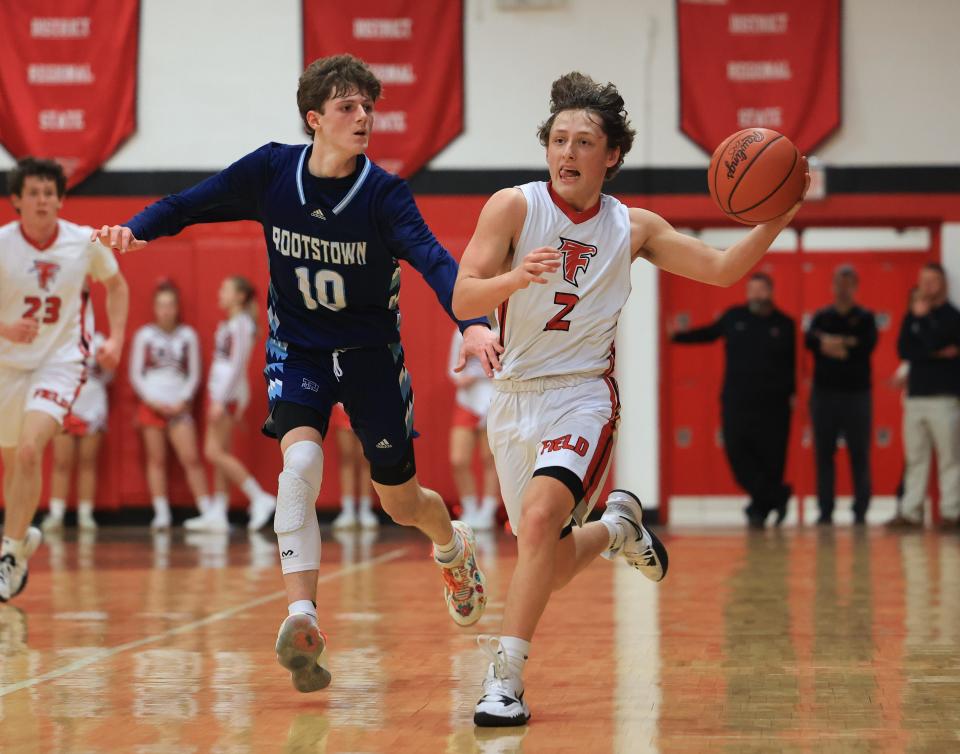 Field senior Jimmy Cultrona looks to fire a pass across court with Rootstown senior Nick Wancik in pursuit during Tuesday night’s game at Field High School. The Falcons defeated Rootstown 61-50.