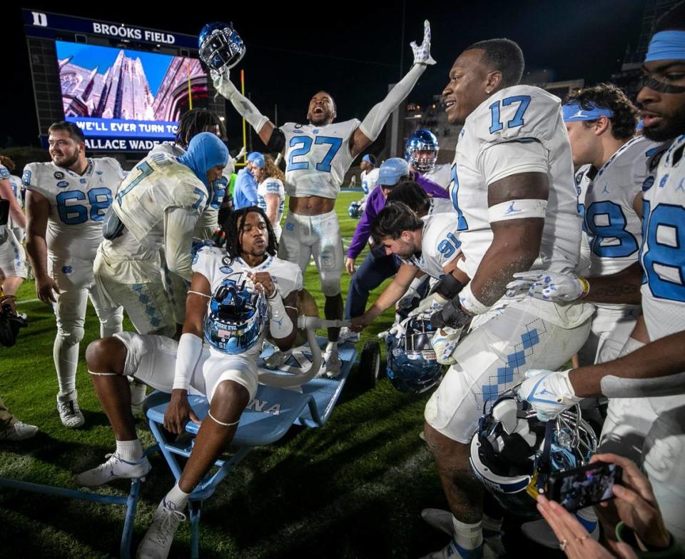 North Carolina kicker Ben Kieran (91) rings the victory bell as teammate Chris Collins (17) rides off the field to the locker room following the Tar Heels 38-35 victory over Duke on Saturday, October 15, 2022 at Wallace-Wade Stadium in Durham, N.C.