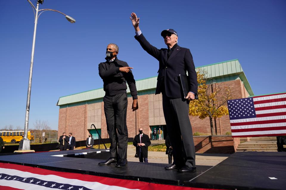 Former Vice President Joe Biden, right, and former President Barack Obama greet each other at a rally at Northwestern High School in Flint, Mich., on Oct. 31, 2020.