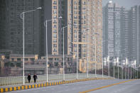 FILE - In this Jan. 28, 2020, file photo, people wearing face masks walk down a deserted street in Wuhan in central China's Hubei Province. As the coronavirus spreads around the world, International health authorities are hoping countries can learn a few lessons from China, namely, that quarantines can be effective and acting fast is crucial. On the other hand, the question before the world is to what extent it can and wants to replicate China’s draconian methods. (AP Photo/Arek Rataj, File)