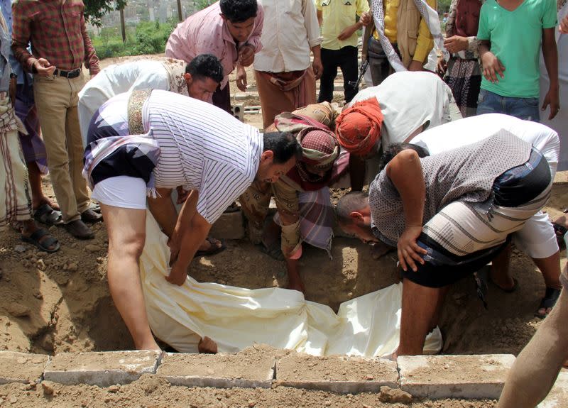 FILE PHOTO: Mourners lower the body of a man, suspected to have died from the coronavirus disease (COVID-19) in Taiz