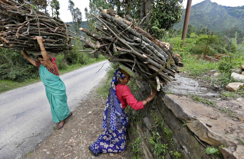 In this Aug. 25, 2012 photo, Devki Bisht, mother of Shoba Bisht who works at B2R, center, picks a up a load of firewood to use at home in Simayal, India. Devki insisted that her daughter Shoba be allowed to work when her son tried to talk her out of it, and now Shoba has helped the family by providing money for building additional rooms as well as her brother's hospital bills. (AP Photo/Saurabh Das)