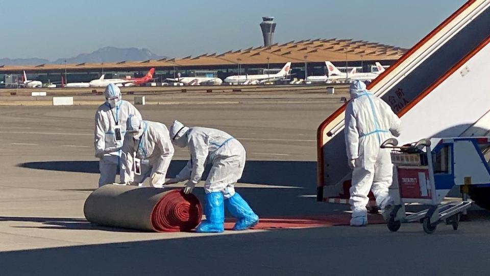 Workers in protective suits roll out a carpet near an airplane carrying German Chancellor Olaf Scholz as he arrives for a visit in China, at the Beijing Capital International Airport, in Beijing, China November 4, 2022