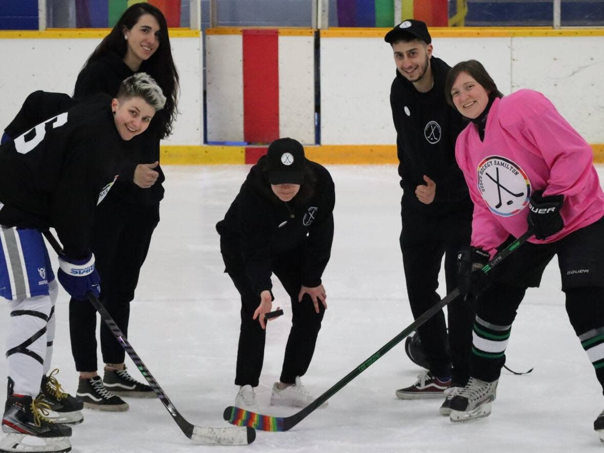 Queer Hockey Hamilton organizers, including Katie Campanella, back left, participate in a ceremonial puck drop at the organization's first tournament, held in April at the Wentworth Sports Complex. (Submitted by Queer Hockey Hamilton - image credit)