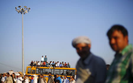 Demonstrators from the Jat community sit on top of a school bus as they block the Delhi-Haryana national highway during a protest at Sampla village in Haryana, India, February 21, 2016. REUTERS/Adnan Abidi