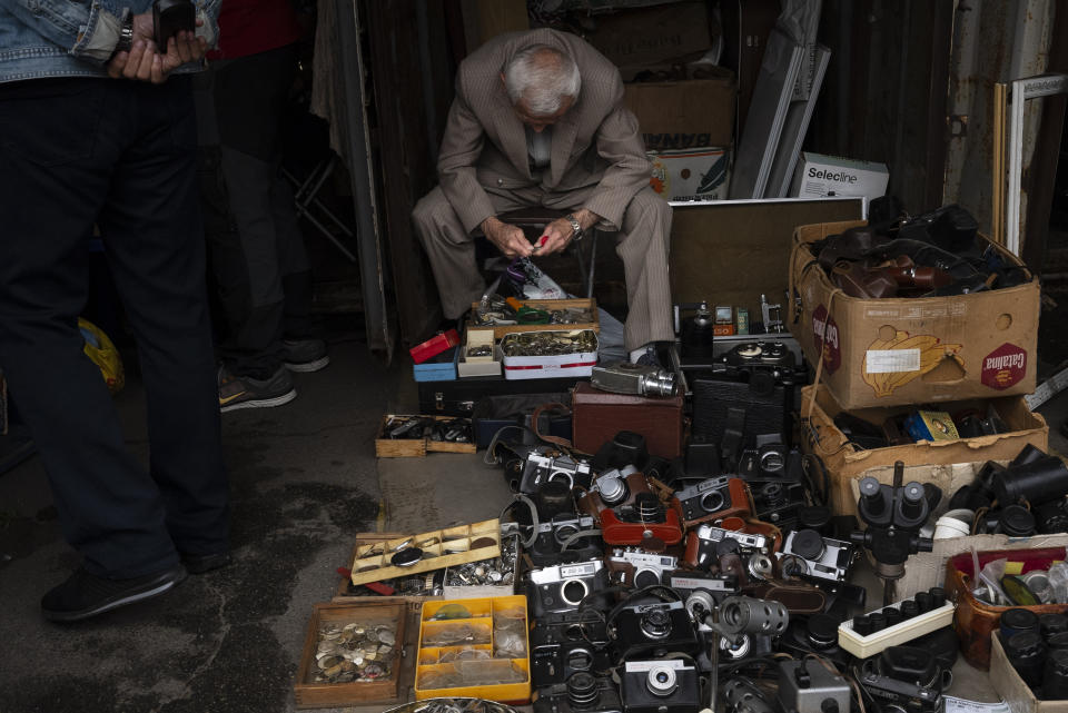 Un hombre vende viejas cámaras de fotos y accesorios en su puesto en un mercado callejero en Kiev, Ucrania, el 8 de julio de 2023. El vecindario de Pochaina de la capital ucraniana cobra vida cada fin de semana cuando cientos de personas acuden en masa a su famoso mercadillo en busca de tesoros. Cazadores de antigüedades, coleccionistas y muchos otros buscan entre filas que parecen interminables de baratijas y artículos desgastados por el paso del tiempo. (AP Foto/Jae C. Hong)