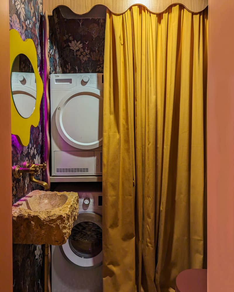 Washer and dryer behind gold curtain in bathroom