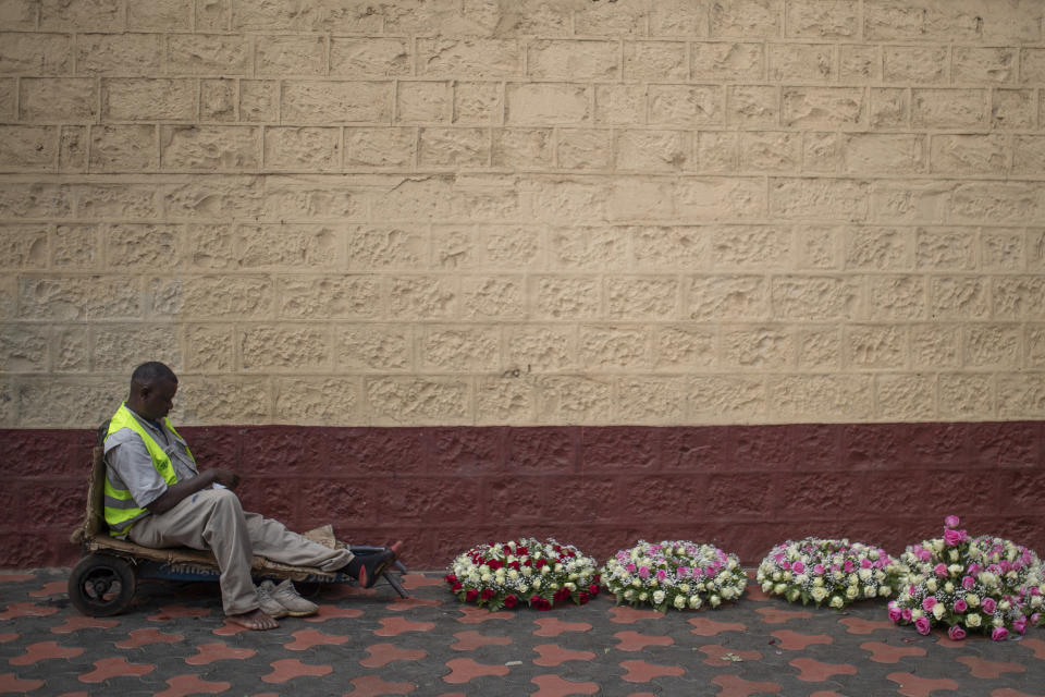 A flower seller waits for customers as he follows provisional election results on a radio, in Nairobi, Kenya, Friday, Aug. 12, 2022. Vote-tallying in Kenya's close presidential election isn't moving fast enough, the electoral commission chair said Friday, while parallel counting by local media dramatically slowed amid concerns about censorship or meddling. (AP Photo/Mosa'ab Elshamy)