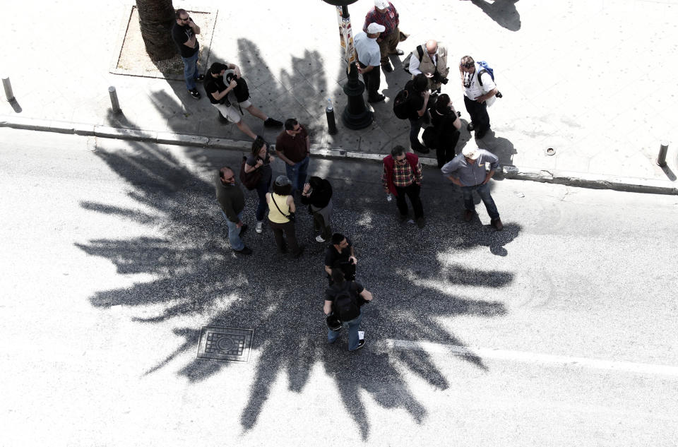 People stand on the shield of a palm tree during a May Day protest in Athens, Tuesday, May 1, 2012. In debt-crippled Greece, more than 2,000 people marched through central Athens in subdued May Day protests centered on the country's harsh austerity program. The Greek elections are scheduled for Sunday, May 6.(AP Photo/Dimitri Messinis)