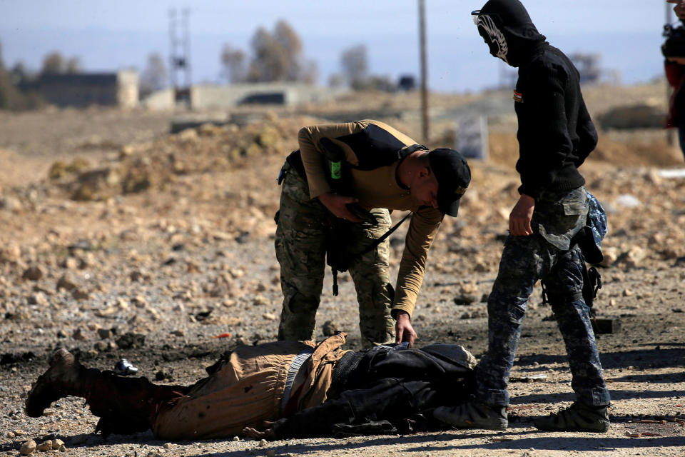 <p>Members of Iraqi security forces look at the body of an Islamic State militant during clashes south of Mosul, Iraq, Feb. 20, 2017. (Alaa Al-Marjani/Reuters) </p>