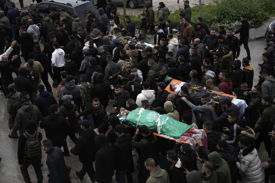 Palestinian gunmen march with bodies of militants draped in the Hamas militant group flag, left, and Palestinian Islamic Jihad, right, killed in an Israeli military raid at Ibn Sina Hospital in the West Bank town of Jenin, Tuesday, Jan. 30, 2024. Armed Israeli undercover forces disguised as women and medical workers stormed the hospital on Tuesday, killing three Palestinian militants. The Palestinian Health Ministry condemned the incursion on a hospital, where the military said the militants were hiding out.(AP Photo/Majdi Mohammed)