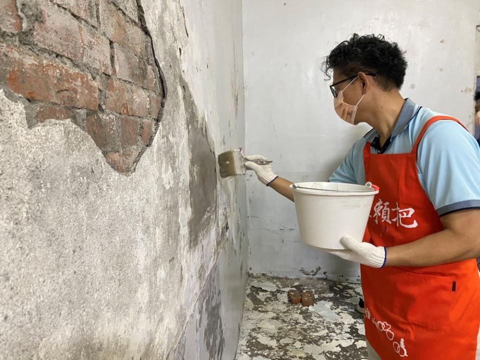 《圖說》志工專心修補破損牆面與漆上防水漆。〈社會局提供〉