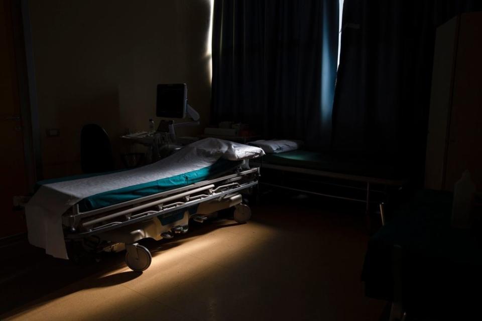 An empty hospital bed mostly in the shadows