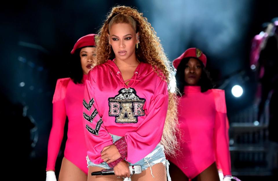 Beyoncé, in a pink sweatshirt embellished with "ΒΔΚ" and denim cut-offs, performs on stage at Coachella.