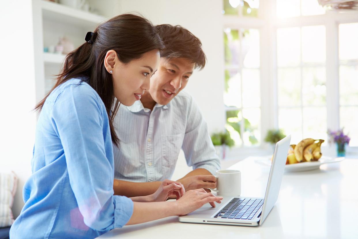 Asian couple looking at laptop in kitchen