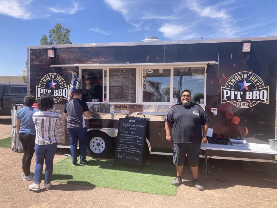Joe Martinez, owner of Smokin' Joe's Pit BBQ, stands in front of his food truck while customers make a line on a Friday afternoon. The food truck is reaching a year milestone.