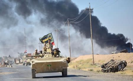 Iraqi army members ride a tank on the outskirts of Hawija, Iraq October 4, 2017. REUTERS/Stringer