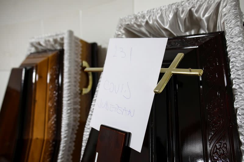 A crucifix and a sheet of paper that reads "Covid County Hospital" is seen on the cover of a coffin prepared for a funeral the next day, in Ploiesti