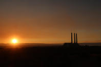 This Aug. 19, 2019, image shows the sun setting behind the coal-fired Navajo Generating Station near Page, Ariz. The power plant will close before the year ends, upending the lives of hundreds of mostly Native American workers who mined coal, loaded it and played a part in producing electricity that powered the American Southwest. (AP Photo/Felicia Fonseca)