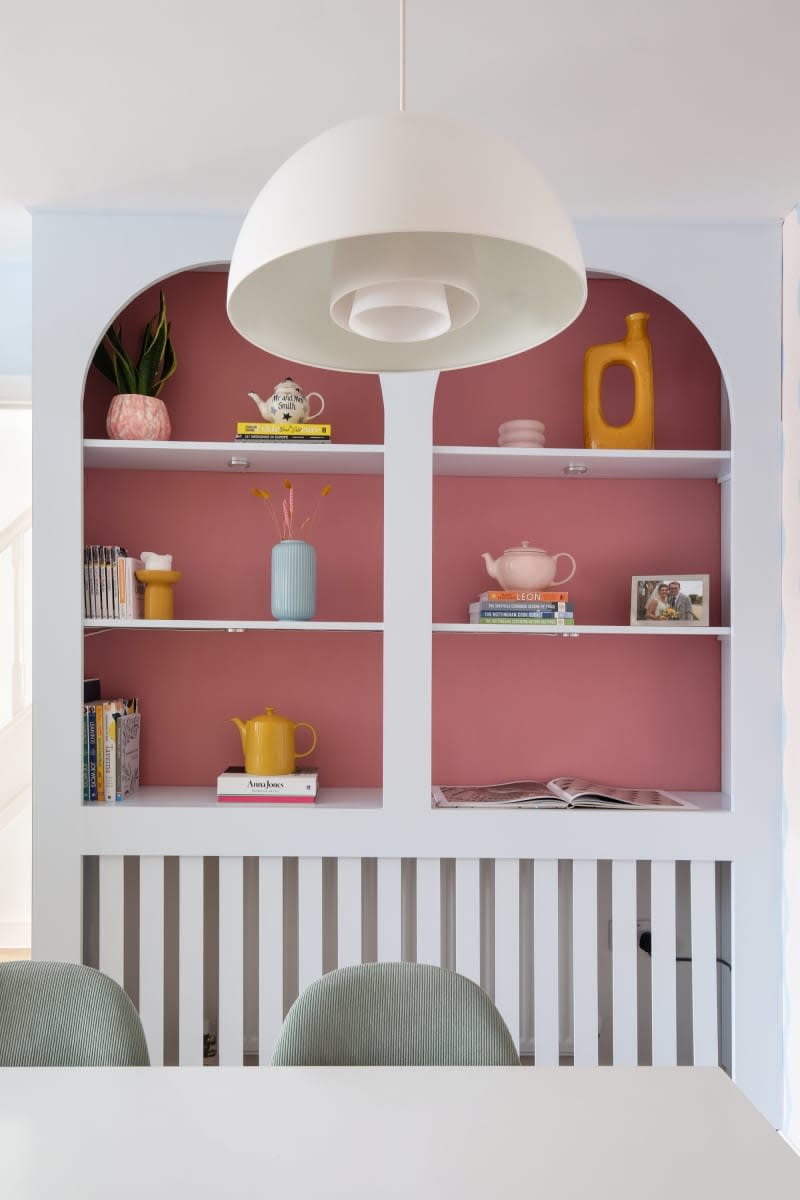 light blue built in cabinets with arched top detail and pink backing, round white lighting fixture and yellow pottery accents