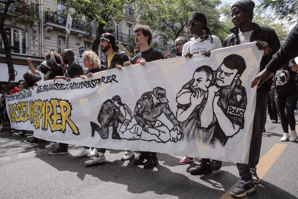 People march holding a banner that reads "Let us breathe" during a protest in memory of Lamine Dieng, a 25-year-old Franco-Senegalese who died in a police van after being arrested in 2007, in Paris, Saturday, June 20, 2020. Multiple protests are taking place in France on Saturday against police brutality and racial injustice, amid weeks of global anger unleashed by George Floyd's death in the US. (AP Photo/Christophe Ena)