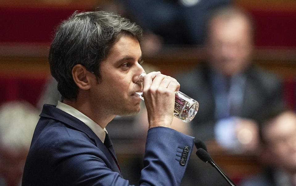 French Prime Minister Gabriel Attal drinks a glass of water during his speech to the lawmakers at the National Assembly in Paris, Tuesday, Jan. 30, 2024. French Prime Minister Gabriel Attal said on Tuesday his top priority is to boost employment in his general policy address to lawmakers, three weeks after he was appointed. Attal is facing his first major challenge as angry farmers are protesting across the country and around Paris against low wages and other problems. (AP Photo/Michel Euler)