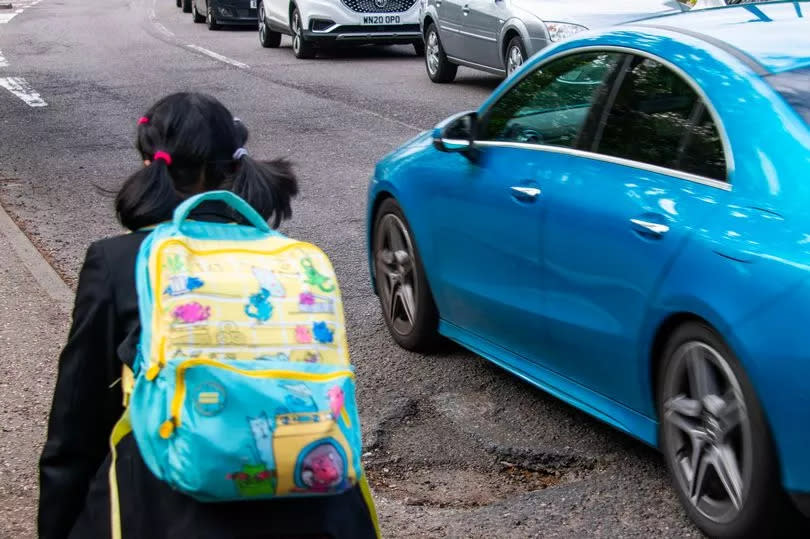 A child walks by one of the huge pot holes in Patching Hall Lane