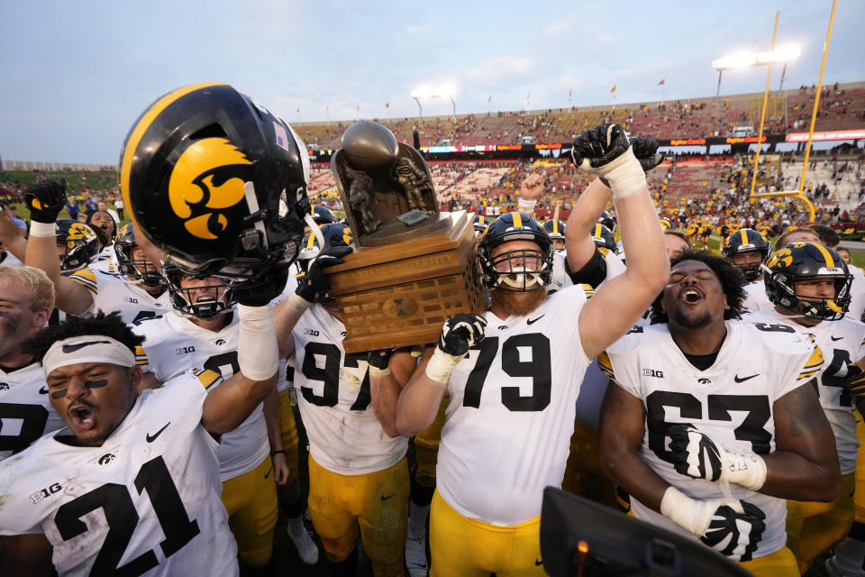 Iowa defensive lineman Zach VanValkenburg (97) and Iowa offensive lineman Jack Plumb (79) hoists the Cy-Hawk Trophy as their team shouts the Iowa fight song celebrating their 27-17 win over Iowa State in an NCAA college football game, Saturday, Sept. 11, 2021, in Ames, Iowa. (AP Photo/Matthew Putney)