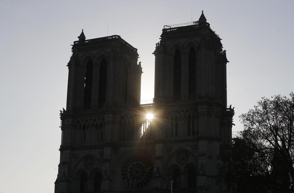 The sun rises between the two towers of Notre Dame cathedral Wednesday, April 17, 2019 in Paris. Nearly $1 billion has already poured in from ordinary worshippers and high-powered magnates around the world to restore Notre Dame Cathedral in Paris after a massive fire. (AP Photo/Francois Mori)