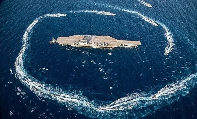  The Iranian mock carrier, essentially a heavily modified barge, the centerpiece of the drills, after being towed out into the Strait of Hormuz. <em>Sepah News</em>