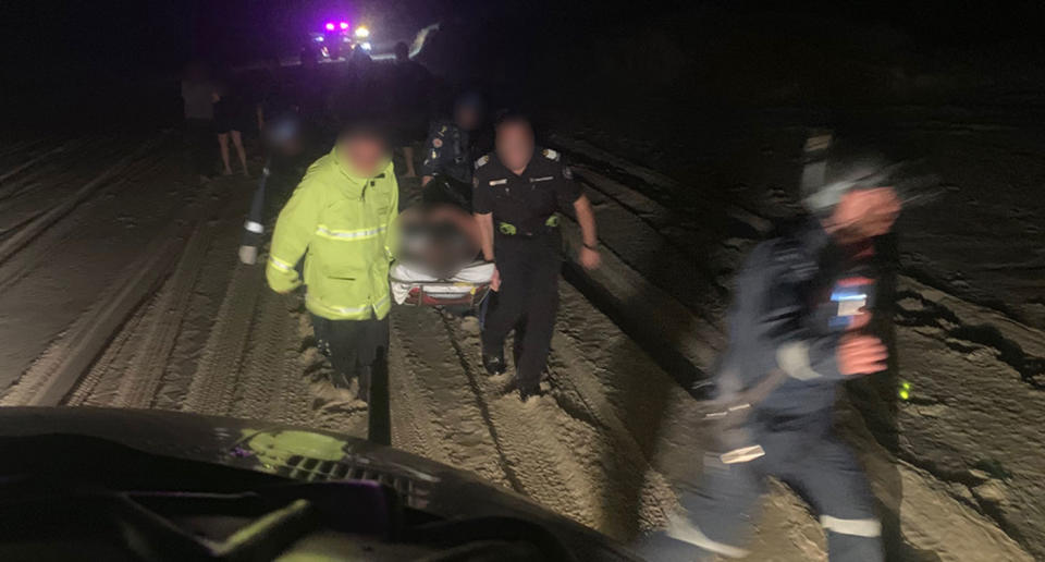 A teenager is picked up on a stretcher at night at Sunshine Coast's Teewah Beach after suffering burns to his body.