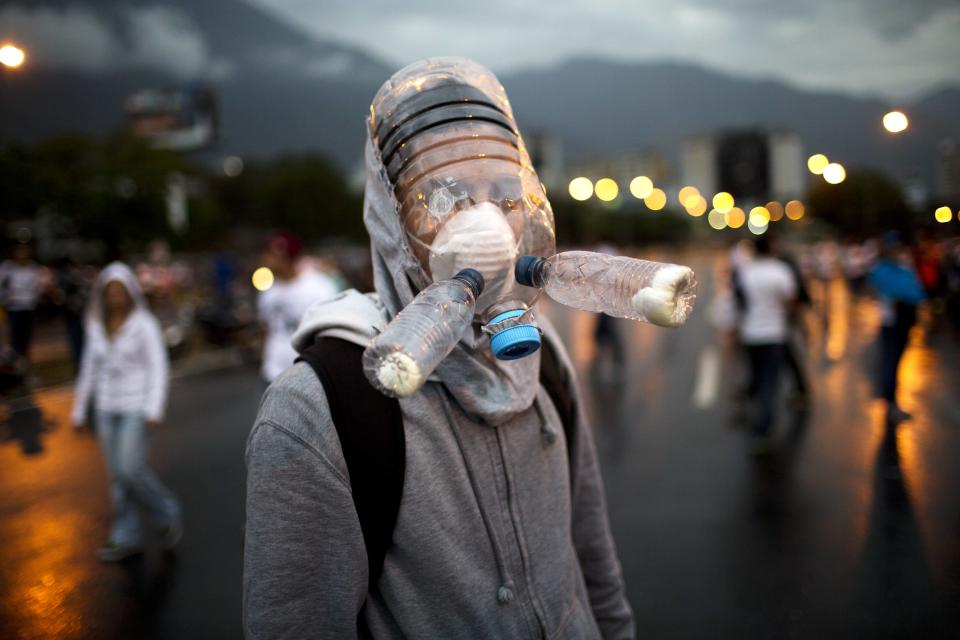 <p>A protester wearing a gas mask made from plastic water bottles poses for a picture during an opposition protest blocking a highway outside La Carlota airport in Caracas, Venezuela, Feb. 18, 2014.(Photo: Rodrigo Abd/AP) </p>