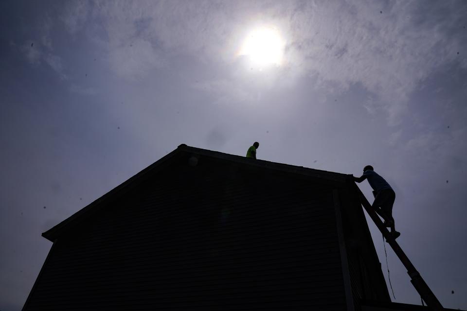 Brian Hoeppner, right, and Even Berrios, install a solar panel on the roof of a home in Frankfort, Ky., Monday, July 17, 2023. Since passage of the Inflation Reduction Act, it has boosted the U.S. transition to renewable energy, accelerated green domestic manufacturing, and made it more affordable for consumers to make climate-friendly purchases, such as installing solar panels on their roofs. (AP Photo/Michael Conroy)